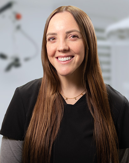 Dental hygienist standing in a treatment room and smiling